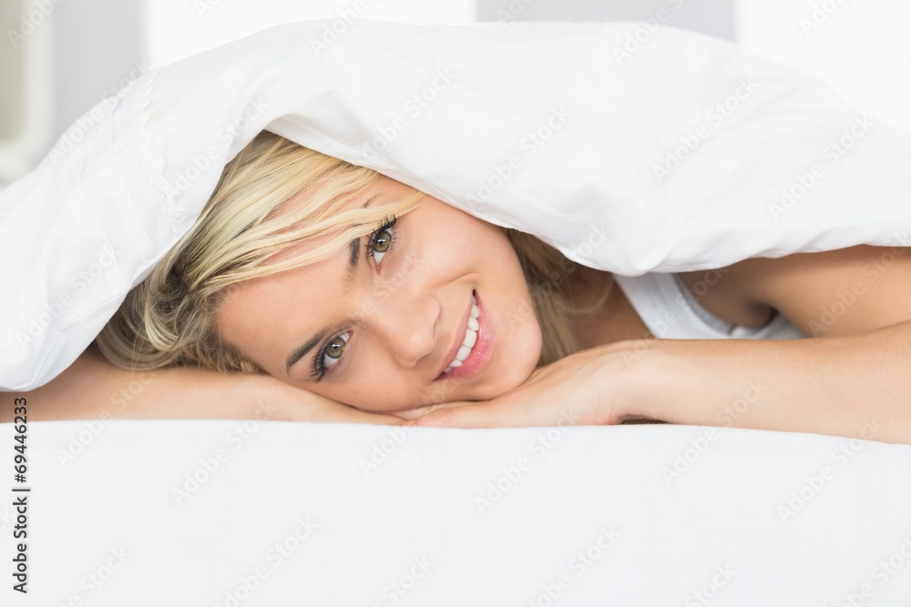 Fototapeta premium Smiling relaxed young woman lying in bed