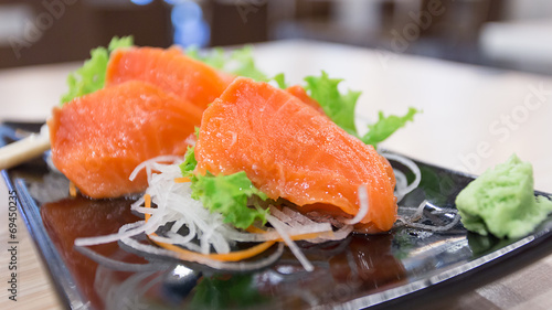 Salmon sashimi on a dish with vegetables , select focus