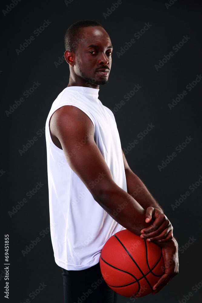 Young african american basketball player over black background