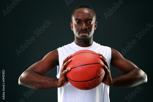 African man holding basketball ball over black background