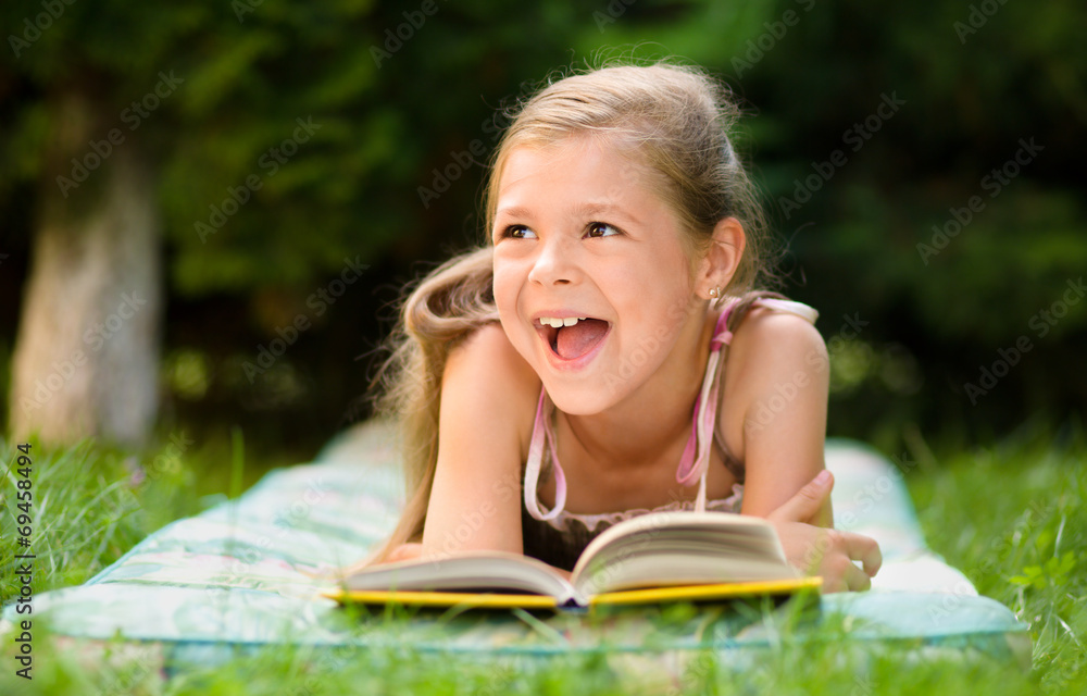 Little girl is reading a book outdoors Little girl is reading a book outdoors