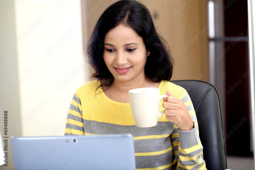 Young woman using tablet computer and drinking coffee Young woman using tablet computer and drinking coffee