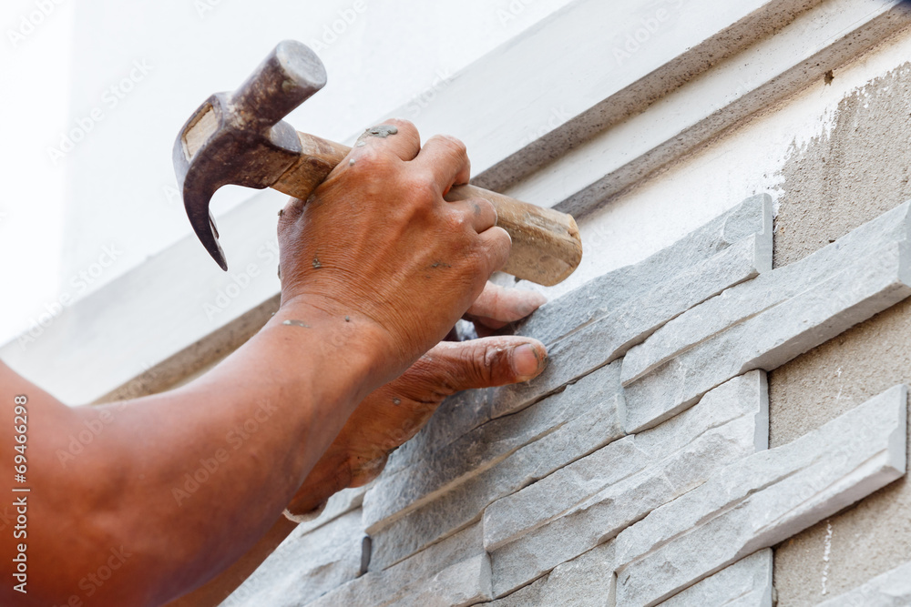 worker install stone wall surface with cement for house