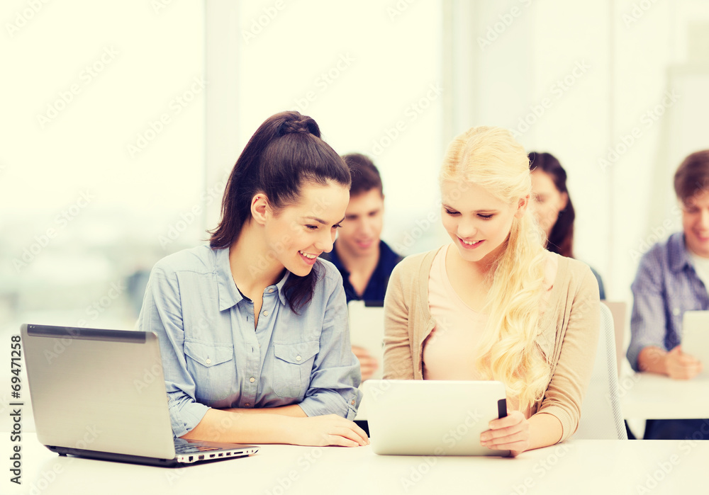 two smiling students with laptop and tablet pc two smiling students with laptop and tablet pc