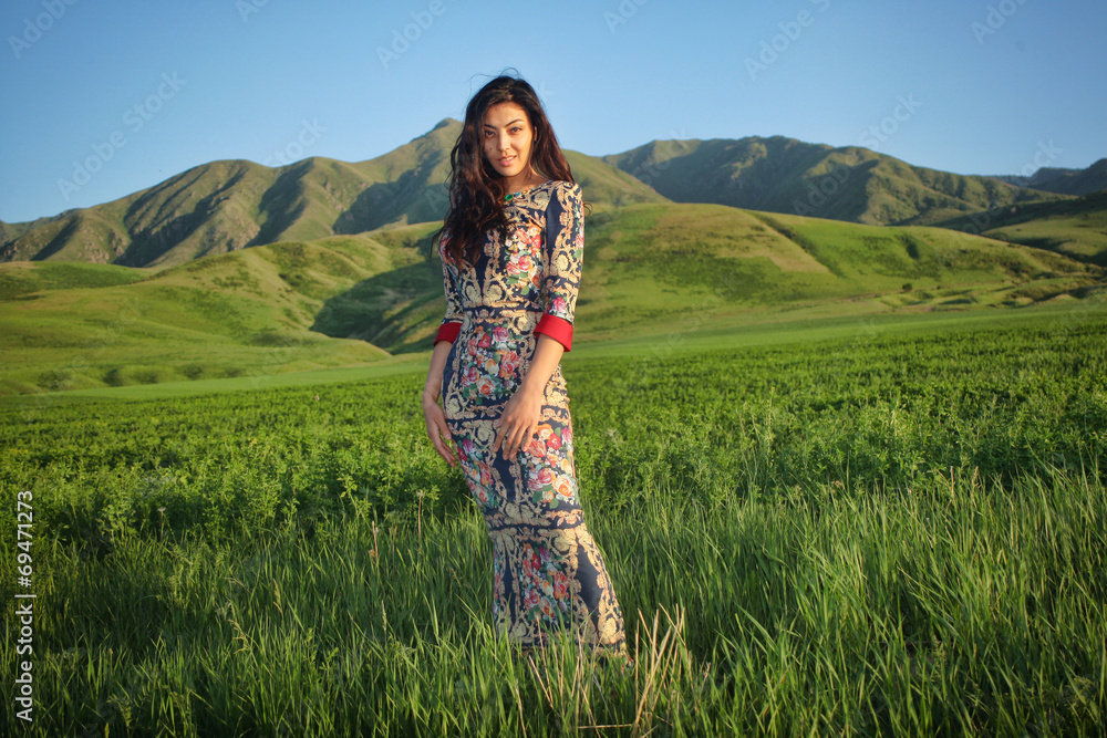 Woman at sunset in a field on a background of mountains Woman at sunset in a field on a background of mountains