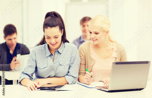 two smiling students with laptop and tablet pc