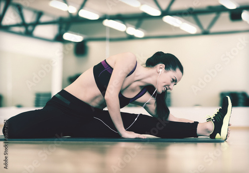 smiling woman stretching on mat in the gym