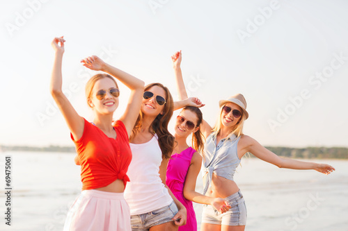 group of smiling women dancing on beach