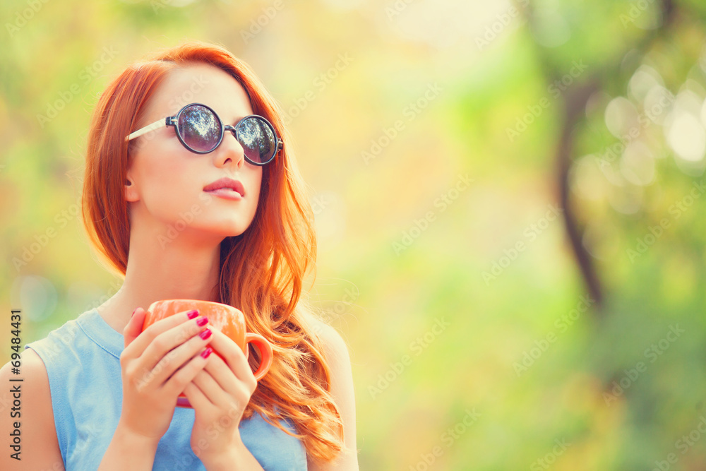 Successful redhead girl winh cup in the autumn park. Successful redhead girl winh cup in the autumn park.