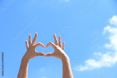 Young girl holding hands in heart shape framing