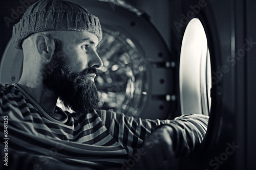 man looking through a porthole of a ship