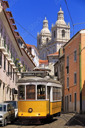 Narrow street in old Lisbon downtown with typical yellow tram