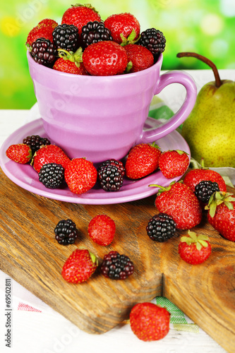 Berries in bowl with pears on table on bright background