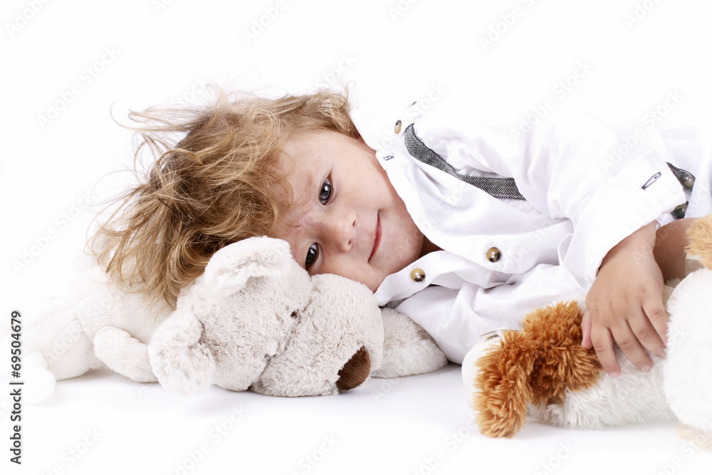 Beautiful little boy lying on the floor holding plush toys Beautiful little boy lying on the floor holding plush toys