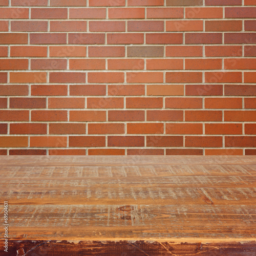 Empty wooden table over brick wall