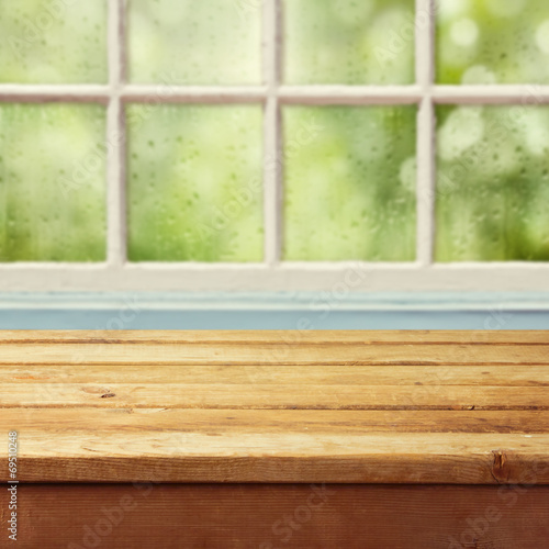 Empty wooden deck table and window with rain drops