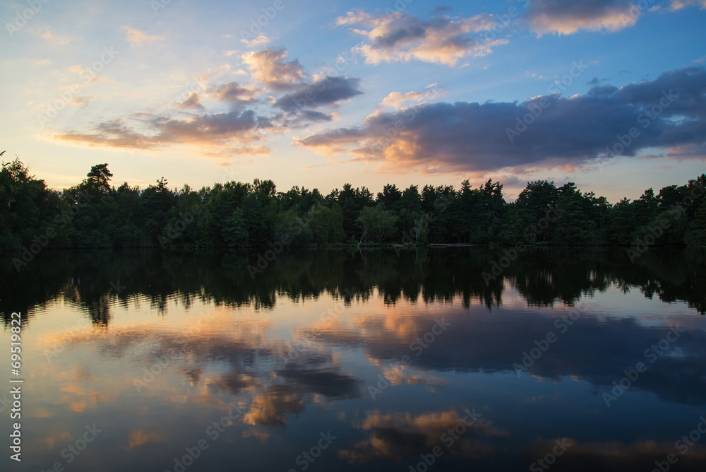 Summer sunset relfected in calm lake landscape