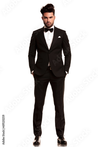 Photo man wearing tuxedo standing with hands in pockets
