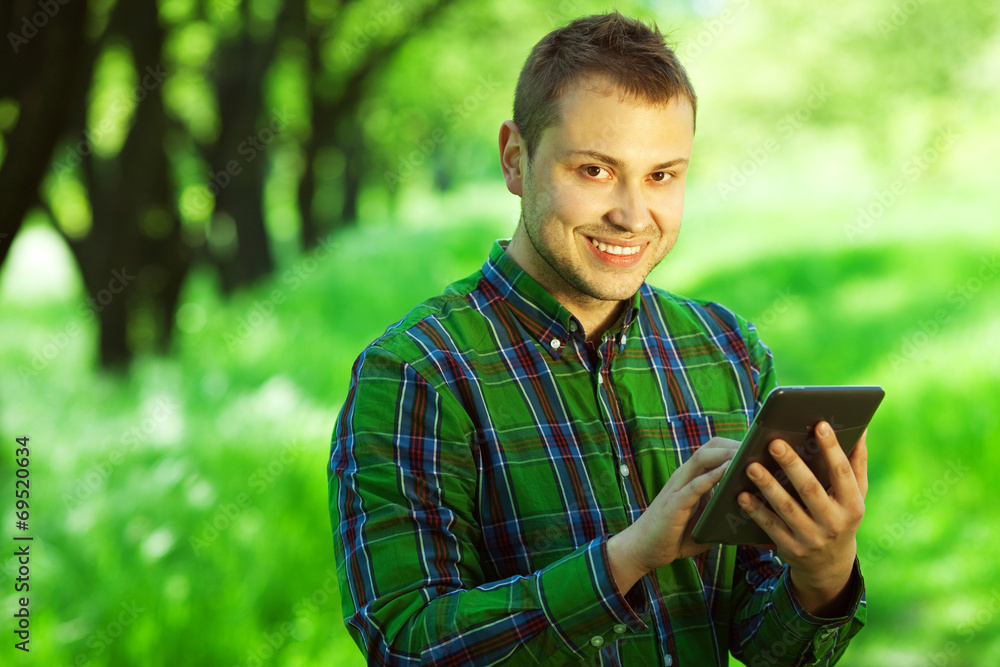 Gadget user concept. Hipster guy with tablet in forest Gadget user concept. Hipster guy with tablet in forest