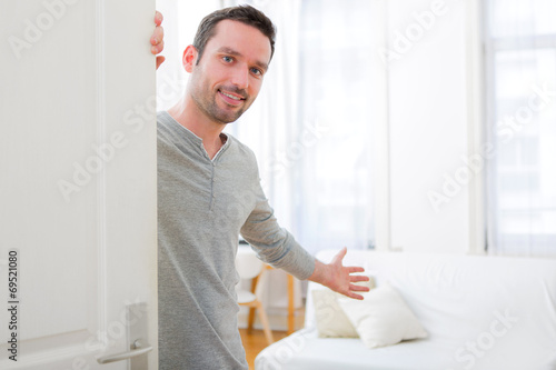 View of a Young attractive man welcoming you in his house photo