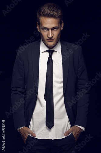 Cool businessman standing on dark background