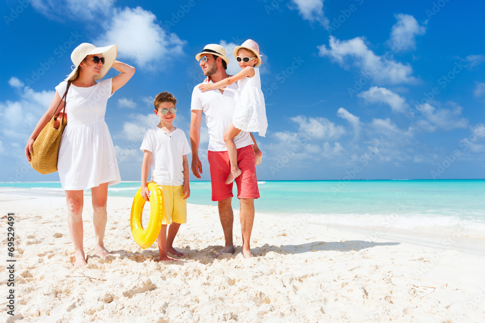 Family on a tropical beach vacation - obrazy, fototapety, plakaty 