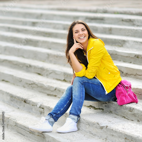Happy young girl sitting on the stairs and smiling © paultarasenko