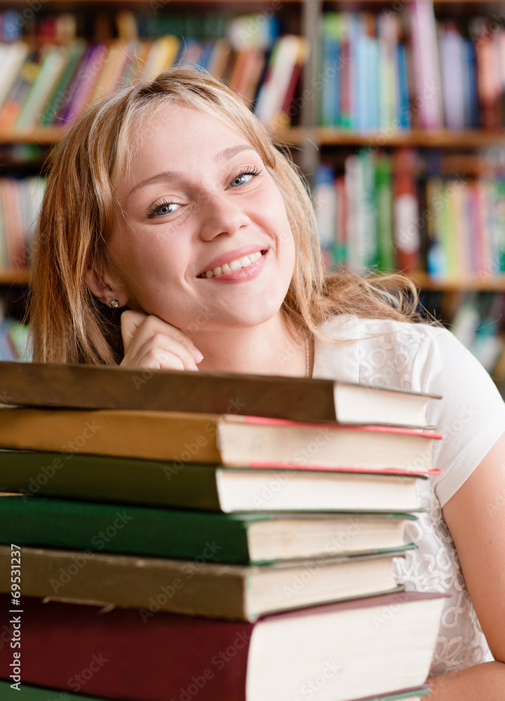 Portrait of a female student with pile books in library Portrait of a female student with pile books in library