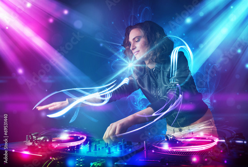 Energetic Dj girl mixing music with powerful light effects © ra2 studio