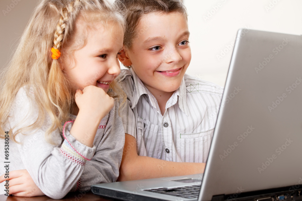 Happy kids playing laptop at home