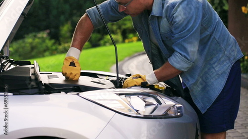 Man checking his car on the driveway and wearing gloves