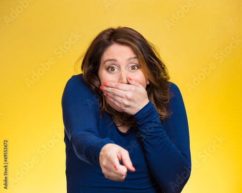 Woman pointing with index finger, laughing yellow background 