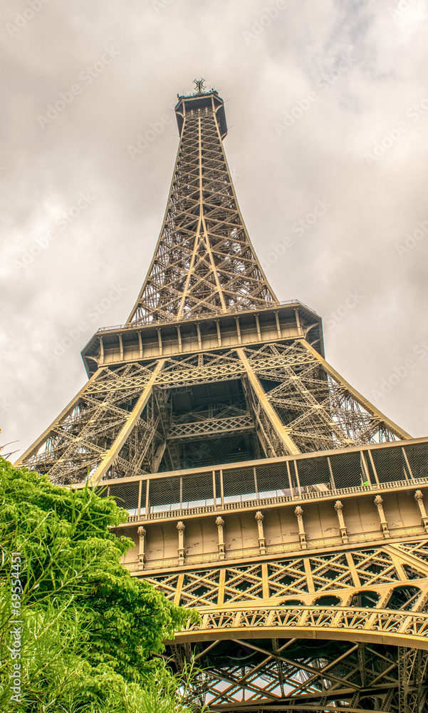 Paris. Eiffel Tower with summer trees on a cloudy sky