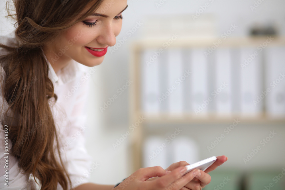 Businesswoman sending message with smartphone sitting in the of