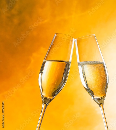 champagne flutes with golden bubbles on golden light background