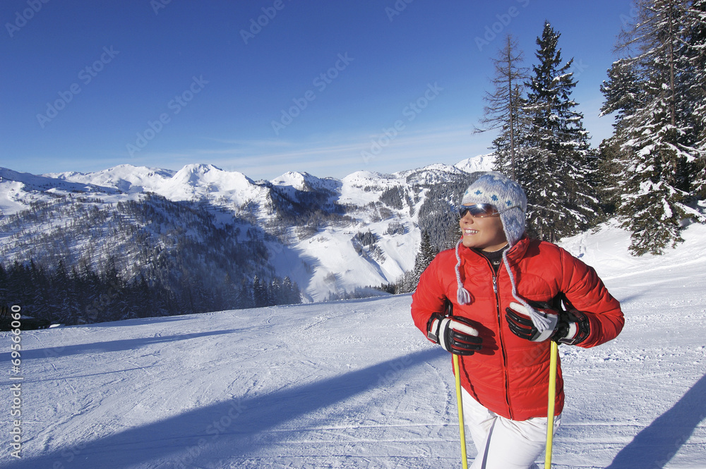 Junge Frau im Schnee hält Skistöcke