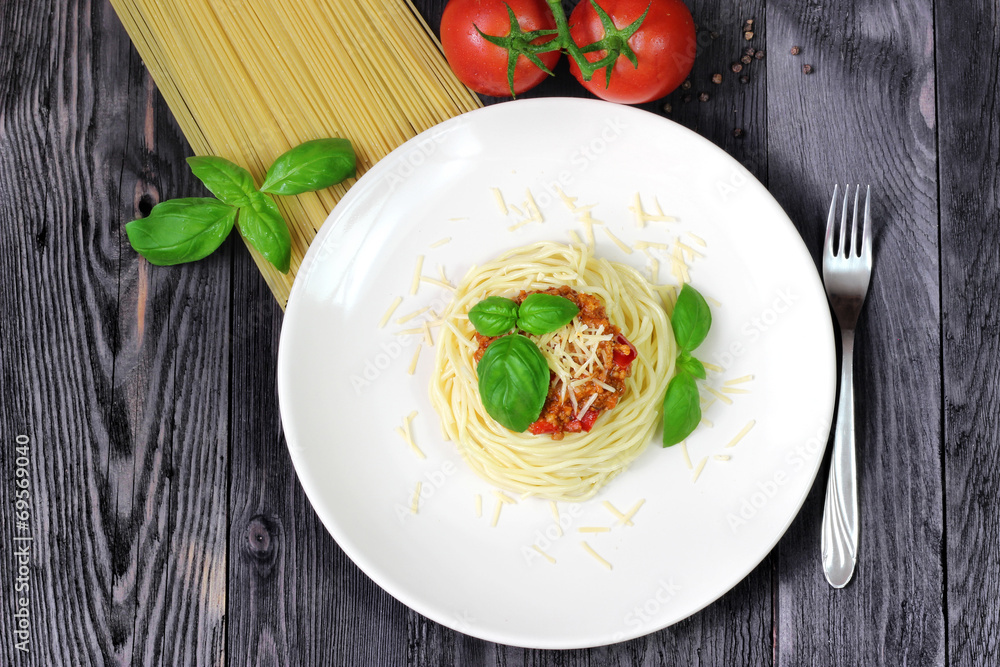 Spaghetti on white plate with pasta, basil and tomatoes