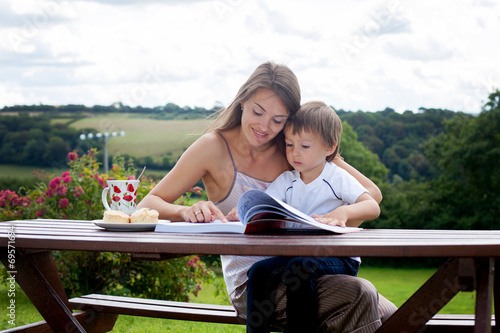 Mother and son, reading a book outdoor, summer day