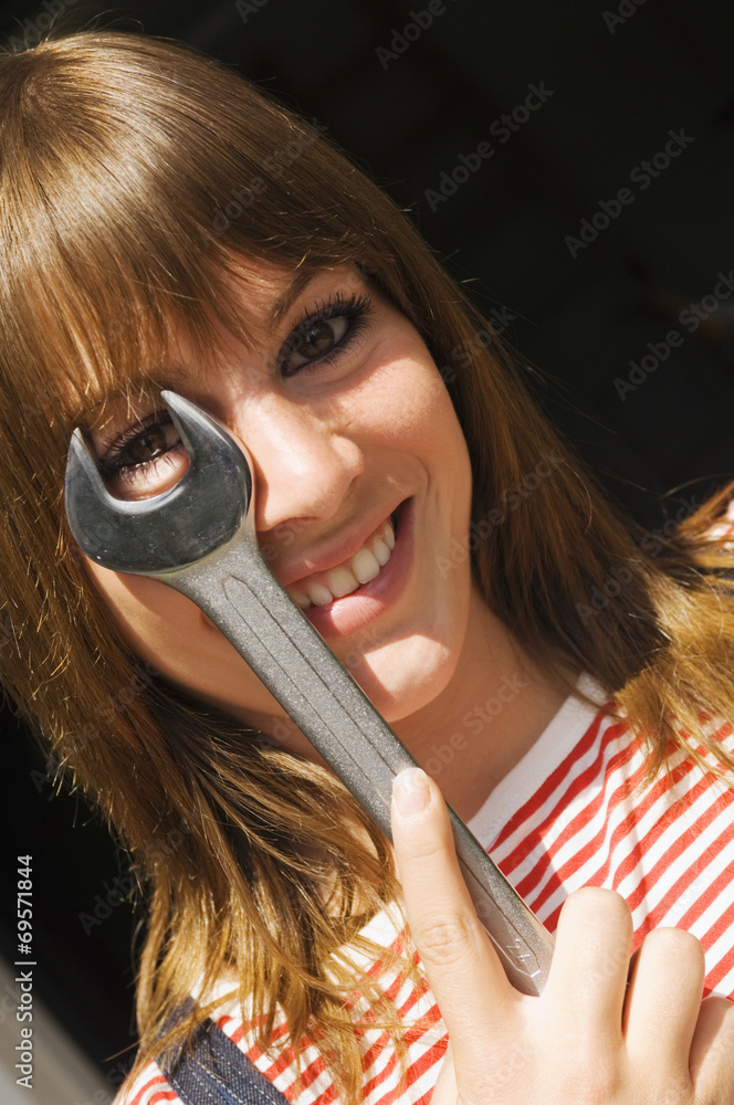 Fototapeta premium Junge Frau, die ein Gabelschlüssel hält, Portrait