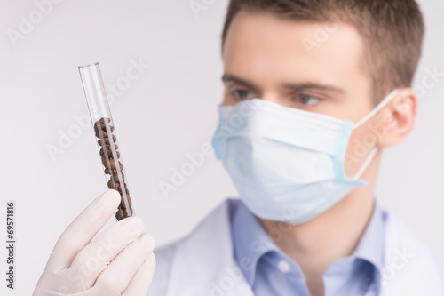man holding test tube and wearing mask.