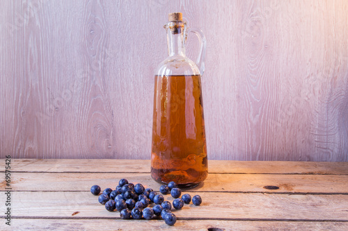 pacharán bottle on wooden table beside sloes photo