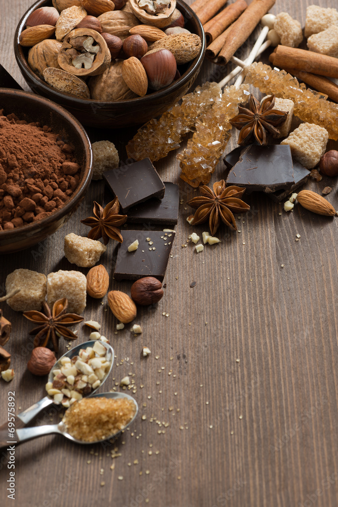 chocolate, cocoa, nuts and spices on wooden background, vertical