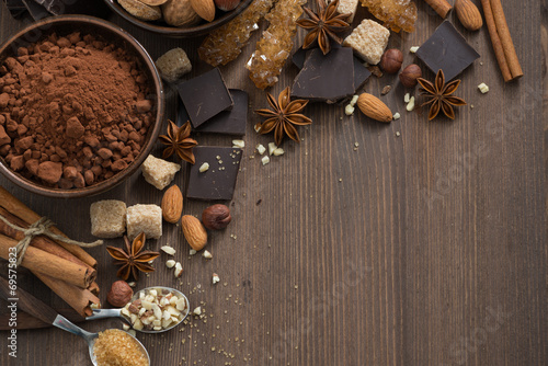 chocolate, cocoa, nuts and spices on wooden background, top view #69575823