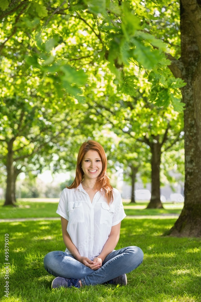 Pretty redhead smiling at camera in the park Pretty redhead smiling at camera in the park