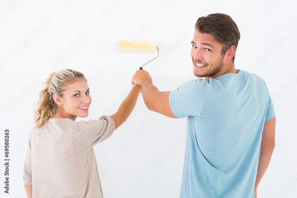 Young couple painting with roller Young couple painting with roller