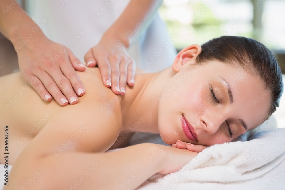 Attractive woman receiving shoulder massage at spa center