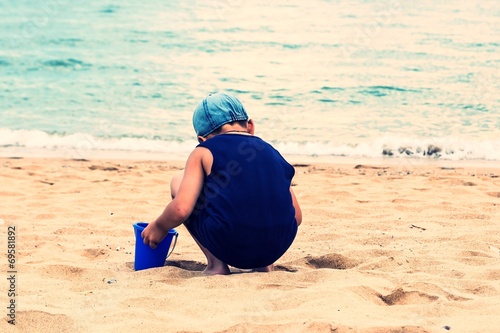 A child playing in the sand on the beach.