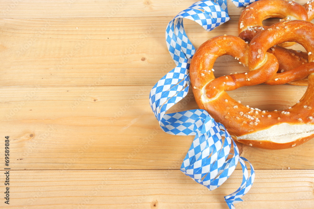 Bayrische Salzbretzel mit Luftschlangen auf Holzbrett Bayrische Salzbretzel mit Luftschlangen auf Holzbrett