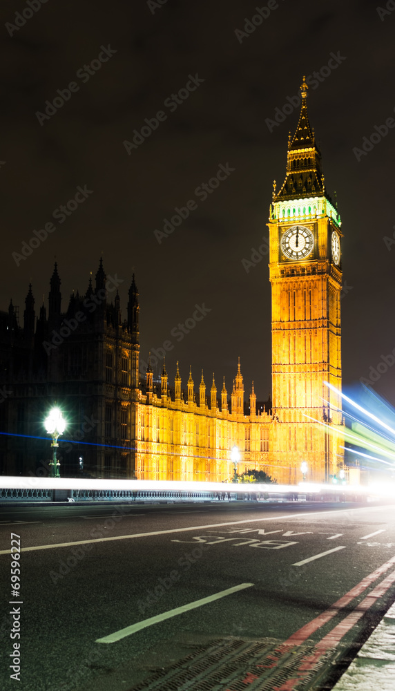 Midnight in London with Big Ben and passing traffic.