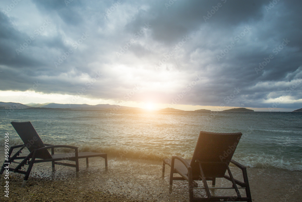 two sun loungers against sea and clouds
